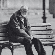 old man sitting alone in a bench with heads down