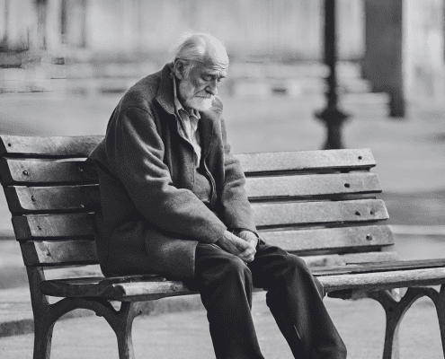 old man sitting alone in a bench with heads down